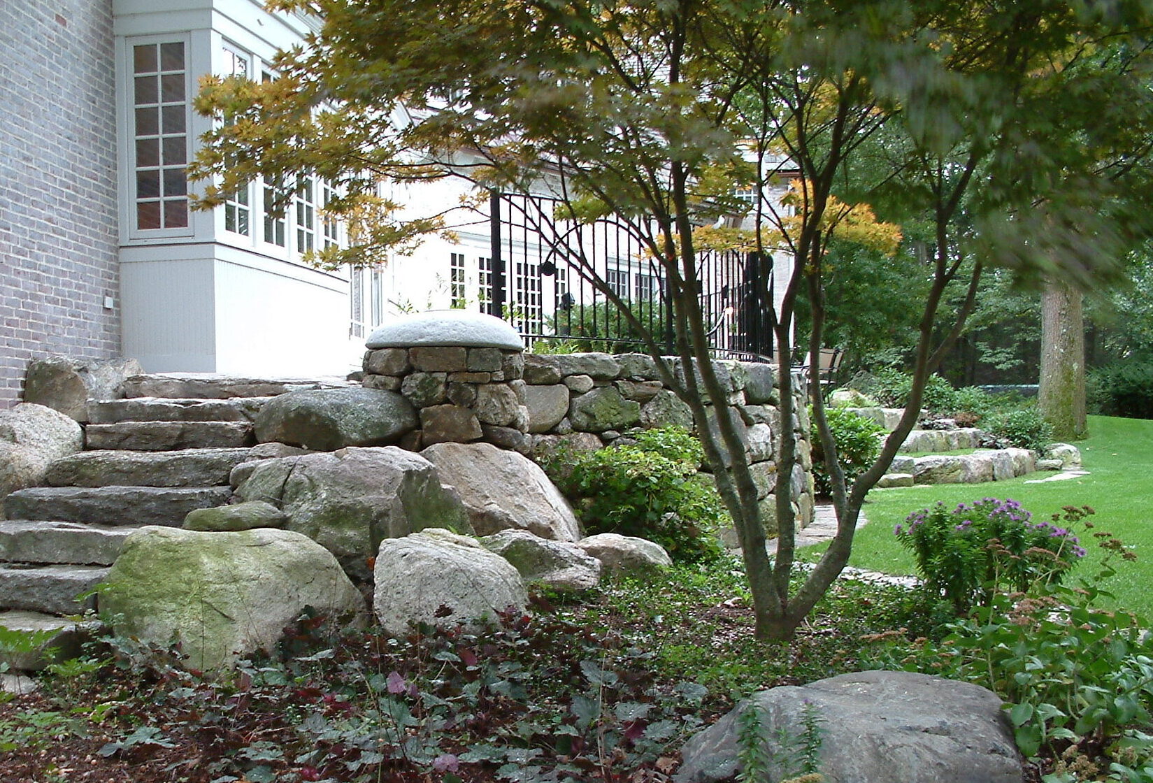 high-end stone landscape design: fieldstone patio and surrounding steps
