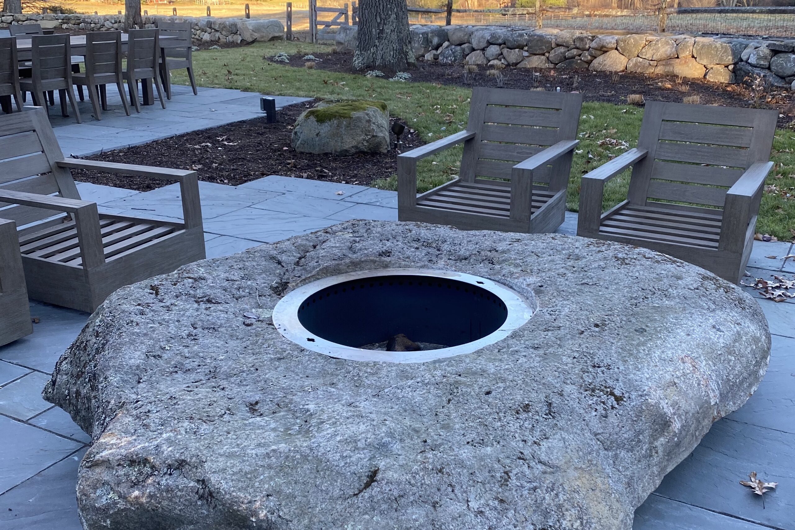 high-end stone design general contracting: Impressively large monolithic stone outdoor fire pit surrounded by inviting chairs.