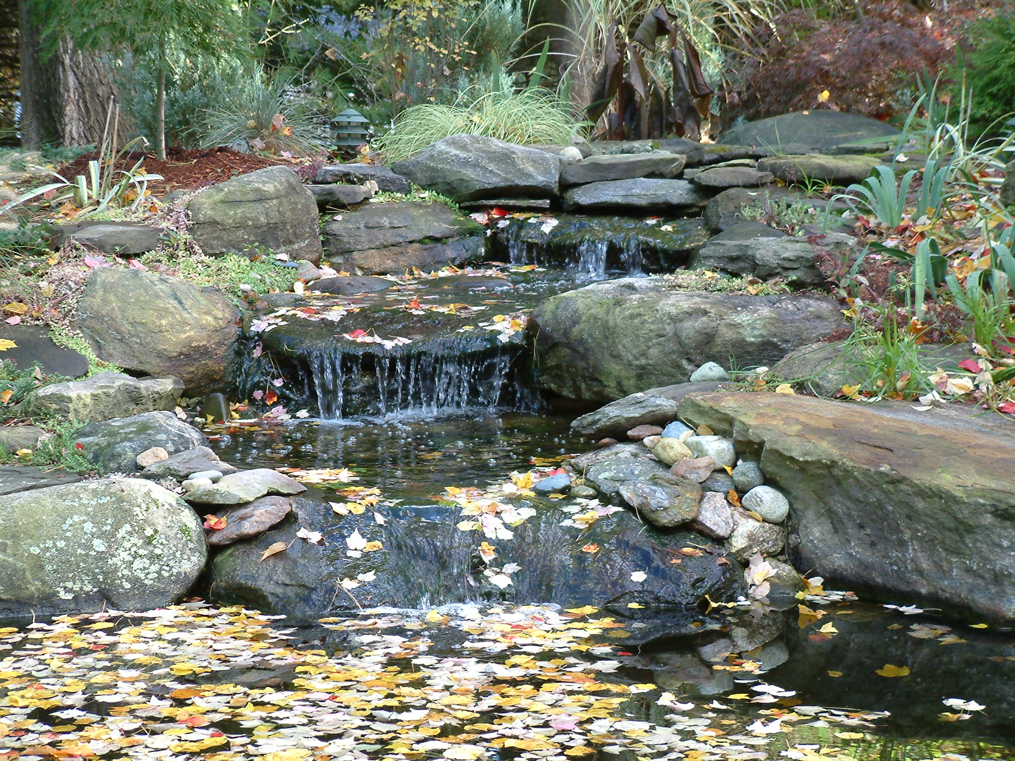 high-end stone landscape design boston: natural stone cascading waterfall and pond.